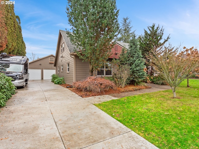 view of front of property featuring a garage, an outdoor structure, and a front lawn