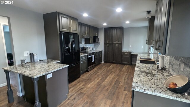 kitchen with appliances with stainless steel finishes, light stone countertops, dark hardwood / wood-style flooring, a kitchen bar, and tasteful backsplash