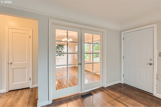 doorway to outside with ornamental molding, french doors, hardwood / wood-style floors, and an inviting chandelier