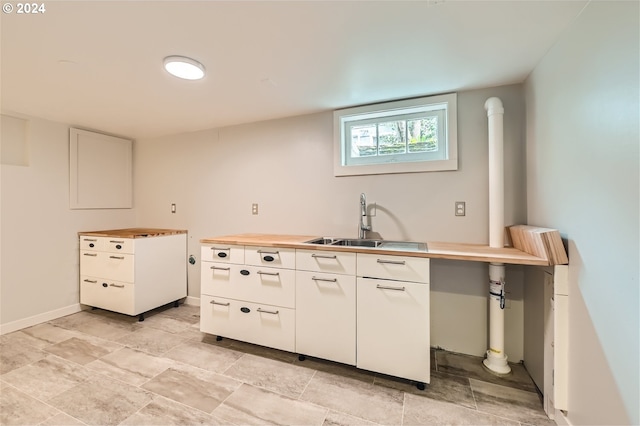 kitchen featuring sink, white cabinetry, and light tile floors