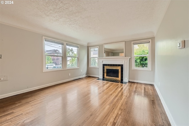 unfurnished living room featuring a tiled fireplace, a textured ceiling, and wood-type flooring