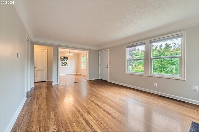 unfurnished living room featuring ornamental molding, a textured ceiling, and hardwood / wood-style flooring