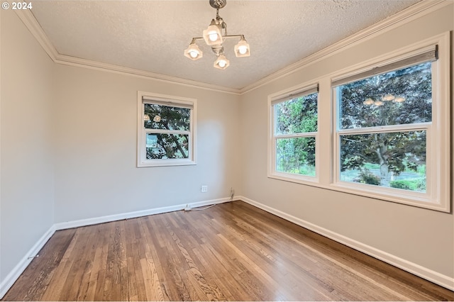 unfurnished room featuring a healthy amount of sunlight, wood-type flooring, a chandelier, and crown molding