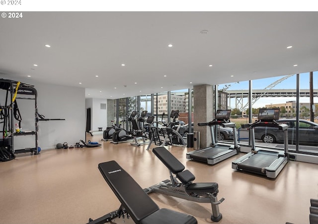 gym with floor to ceiling windows, recessed lighting, and baseboards