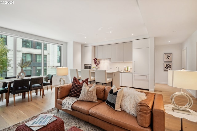 living area with recessed lighting, baseboards, and light wood-style flooring