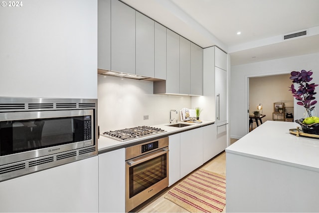 kitchen featuring visible vents, light wood-type flooring, a sink, appliances with stainless steel finishes, and light countertops