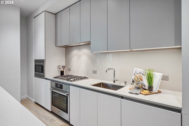 kitchen with modern cabinets, stainless steel appliances, light countertops, and a sink