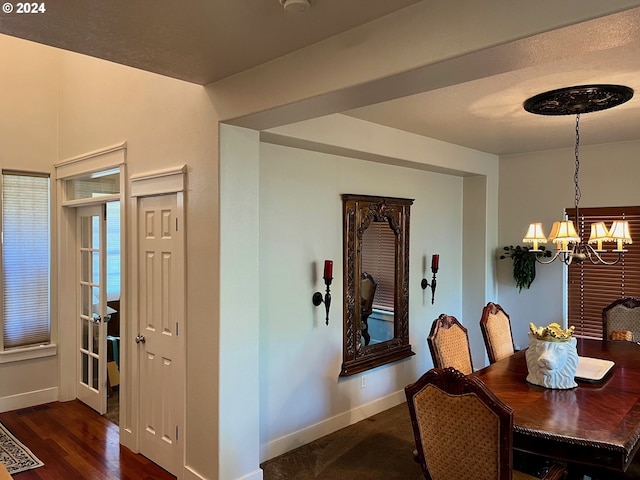 dining area with dark wood-type flooring and a chandelier