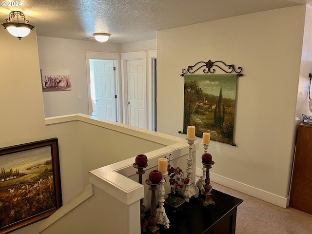 corridor with a textured ceiling and carpet flooring