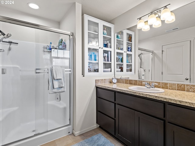 bathroom with tile patterned flooring, vanity, and an enclosed shower