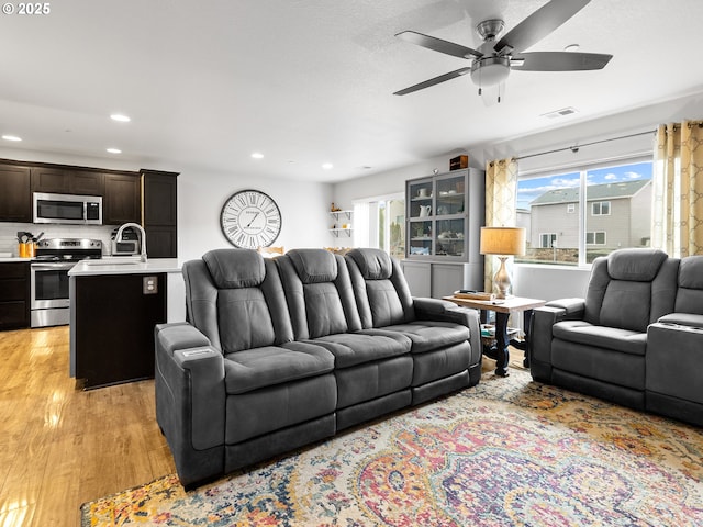 living room with ceiling fan, light hardwood / wood-style floors, and sink