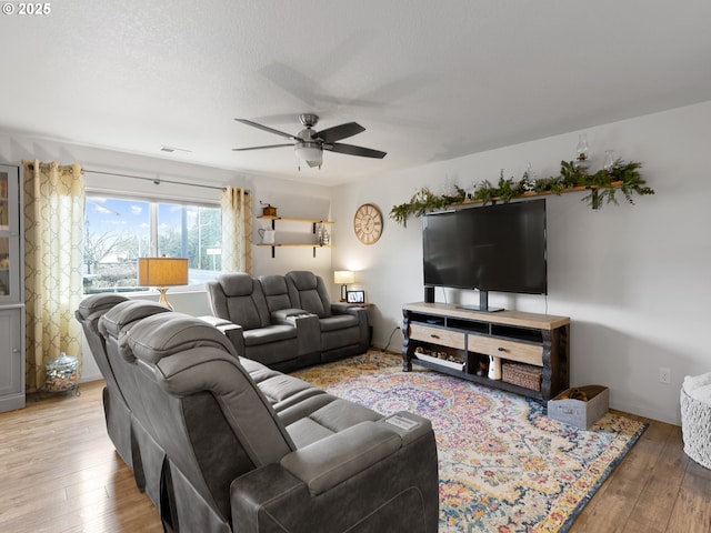 living room featuring ceiling fan, a textured ceiling, and hardwood / wood-style flooring