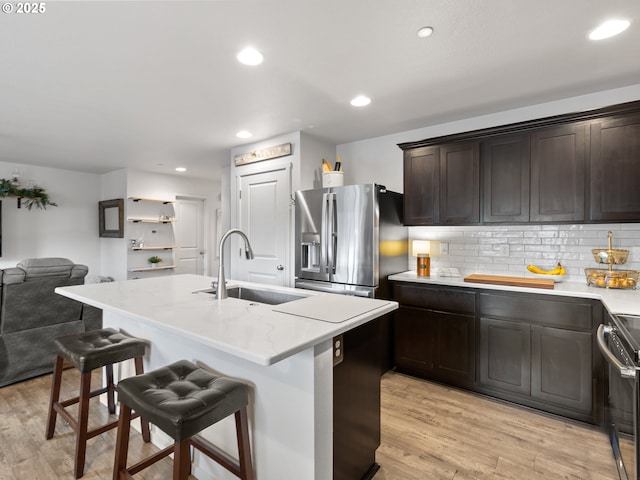 kitchen with a kitchen bar, stainless steel refrigerator with ice dispenser, an island with sink, and sink