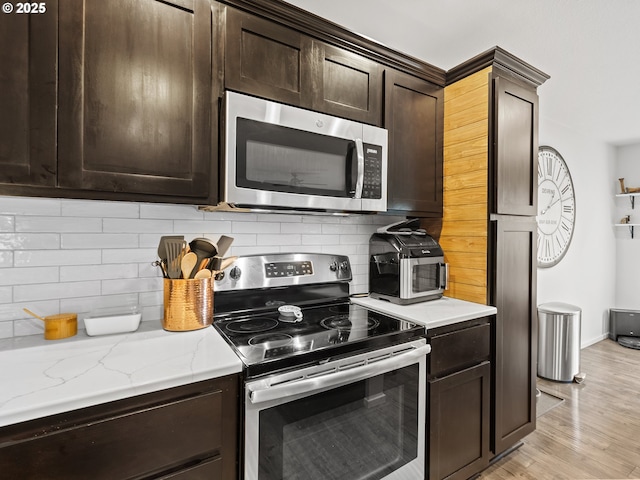 kitchen featuring dark brown cabinets, light wood-type flooring, stainless steel appliances, and tasteful backsplash