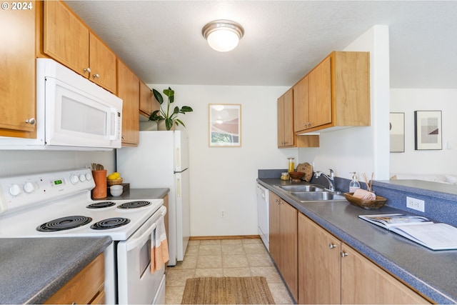 kitchen with white appliances, dark countertops, a sink, and baseboards