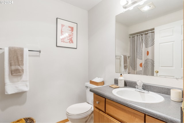 bathroom featuring toilet, vanity, and a shower with curtain