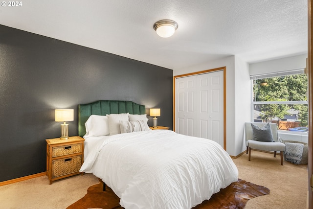 carpeted bedroom with a closet, a textured ceiling, and baseboards