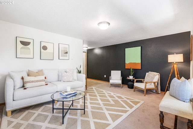 living area with carpet floors, an accent wall, and baseboards