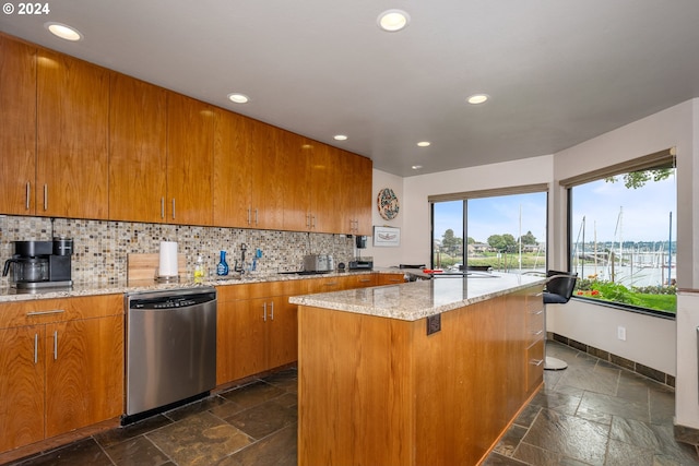 kitchen featuring light stone countertops, dishwasher, tasteful backsplash, a kitchen breakfast bar, and a kitchen island