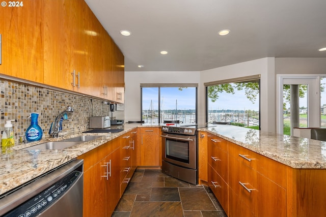 kitchen with backsplash, light stone countertops, sink, and appliances with stainless steel finishes