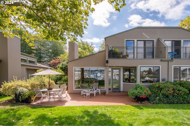 rear view of house featuring a wooden deck and a lawn