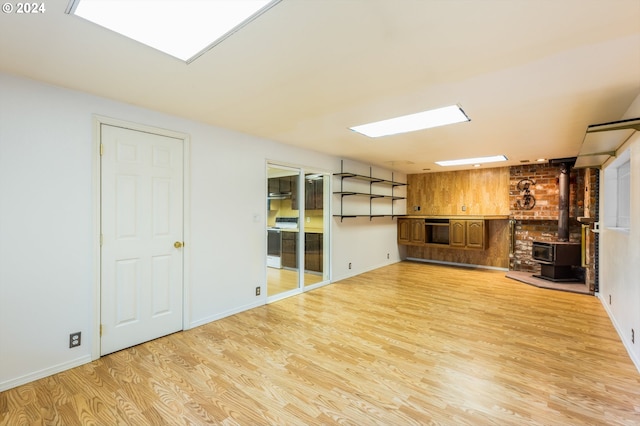 basement with light hardwood / wood-style floors and a wood stove