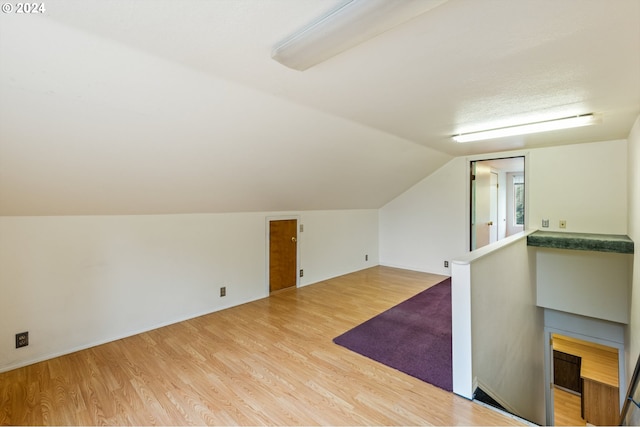 additional living space with vaulted ceiling and light hardwood / wood-style flooring