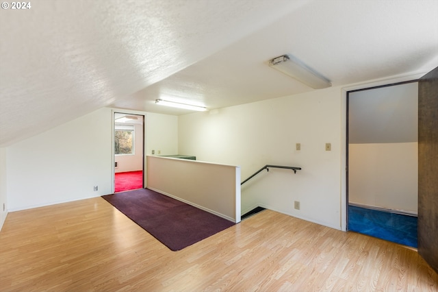 bonus room featuring wood-type flooring, a textured ceiling, and vaulted ceiling