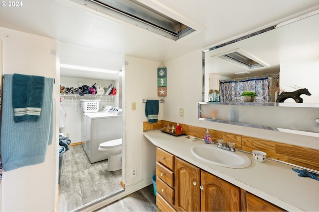 bathroom featuring washing machine and dryer, hardwood / wood-style floors, vanity, and toilet