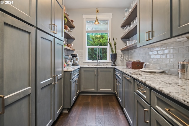 kitchen featuring dark hardwood / wood-style flooring, backsplash, light stone counters, pendant lighting, and gray cabinets