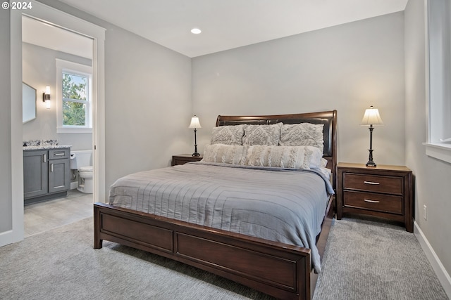 bedroom featuring light carpet and connected bathroom