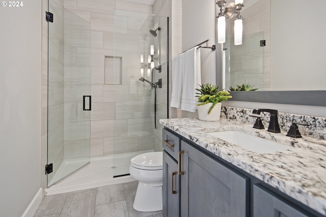 bathroom featuring tile patterned floors, vanity, toilet, and a shower with shower door