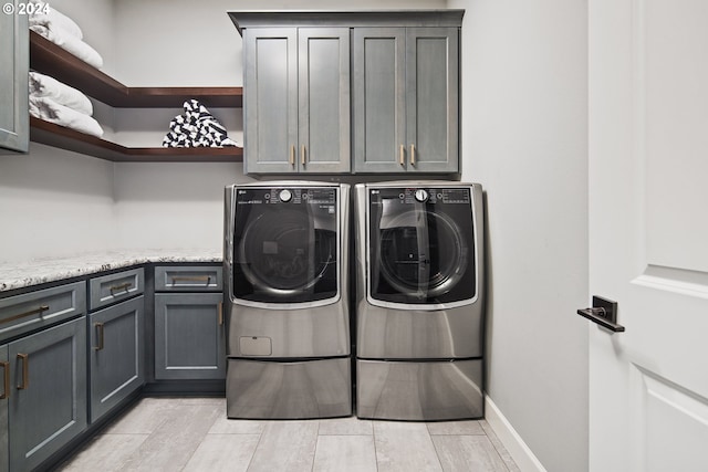 laundry area with cabinets, separate washer and dryer, and light hardwood / wood-style flooring