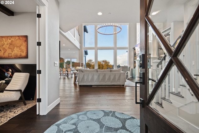 living room featuring beamed ceiling, a towering ceiling, dark hardwood / wood-style flooring, and an inviting chandelier