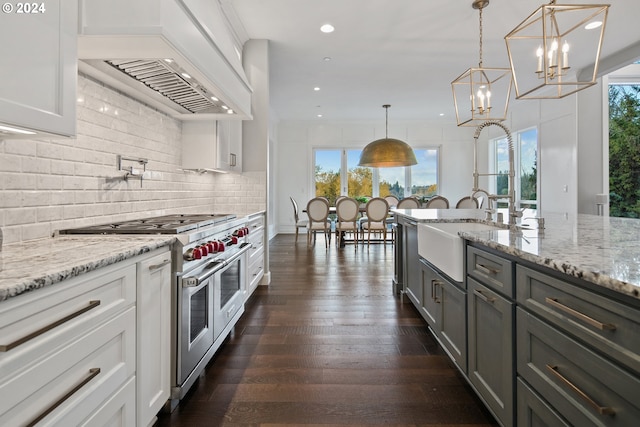 kitchen featuring double oven range, white cabinetry, a wealth of natural light, and pendant lighting