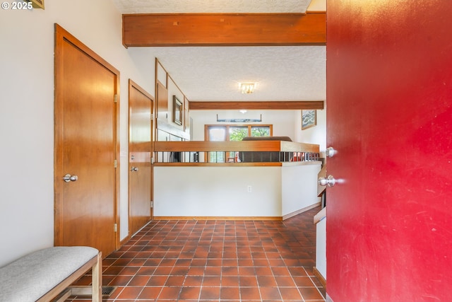 foyer with tile patterned flooring, beamed ceiling, and a textured ceiling