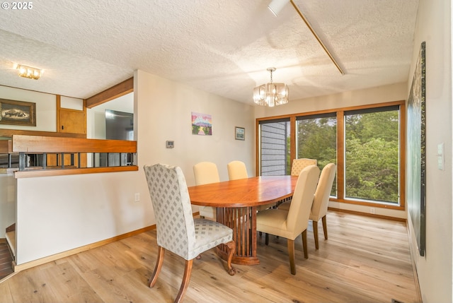 dining room with a notable chandelier, wood finished floors, baseboards, and a textured ceiling