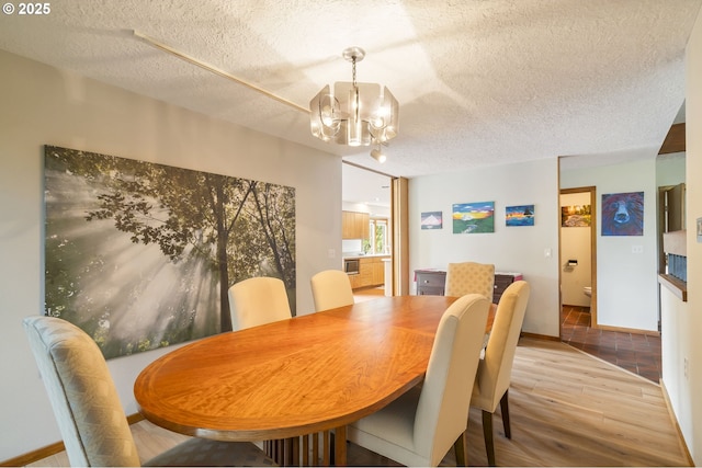 dining area featuring baseboards, a notable chandelier, wood finished floors, and a textured ceiling