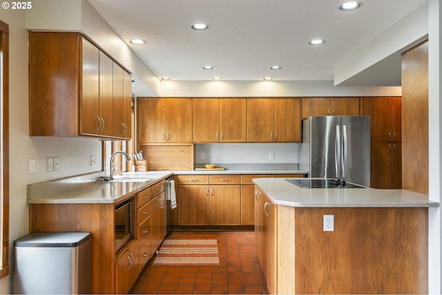 kitchen featuring a sink, recessed lighting, brown cabinetry, stainless steel appliances, and dark tile patterned flooring