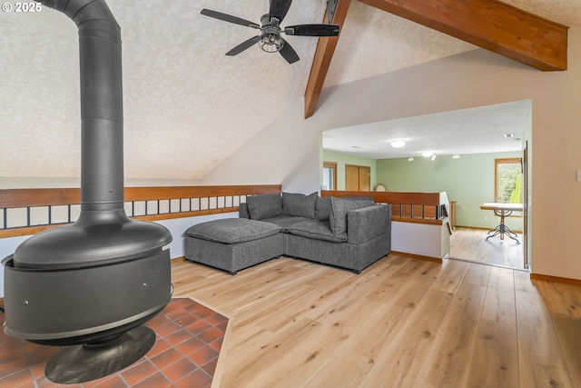 living room featuring a textured ceiling, vaulted ceiling with beams, hardwood / wood-style floors, and a wood stove