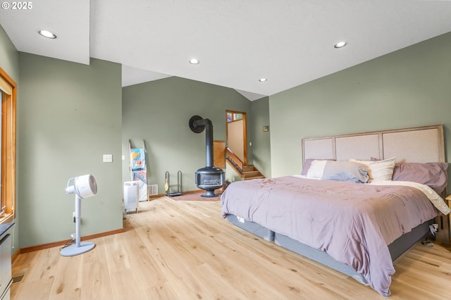 bedroom featuring recessed lighting, baseboards, wood finished floors, and a wood stove