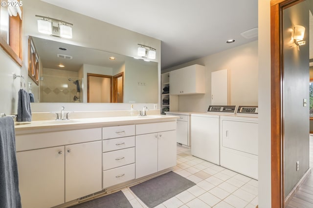 bathroom featuring tile patterned floors, separate washer and dryer, a stall shower, and a sink