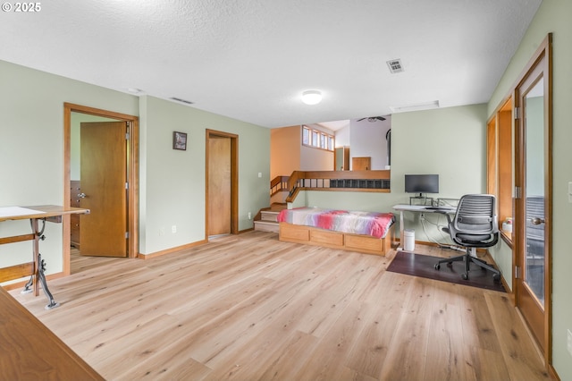 office space with visible vents, a textured ceiling, baseboards, and wood finished floors