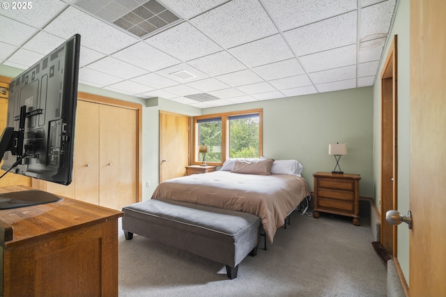 bedroom with a drop ceiling, visible vents, carpet, and a closet