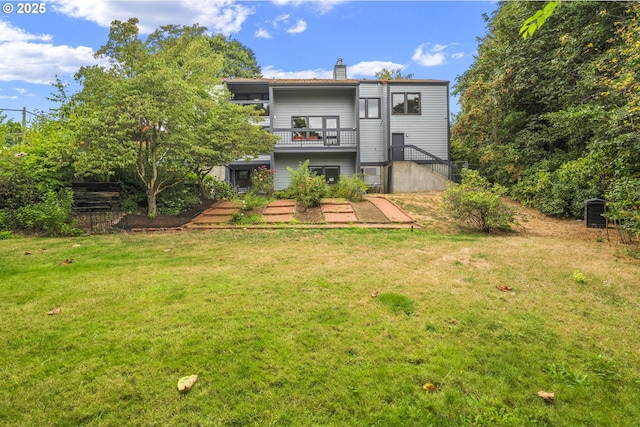 rear view of house featuring a lawn, a chimney, and stairs