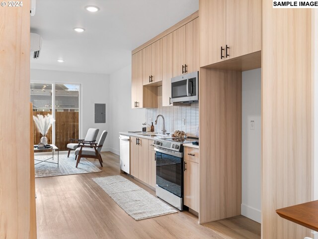 kitchen with tasteful backsplash, light brown cabinets, stainless steel appliances, and light hardwood / wood-style flooring