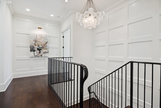 stairway featuring ornamental molding, hardwood / wood-style floors, and an inviting chandelier