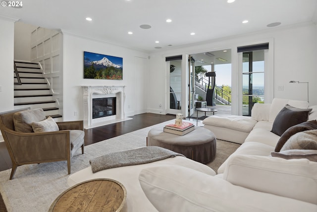 living room with hardwood / wood-style flooring, ornamental molding, a high end fireplace, and built in features