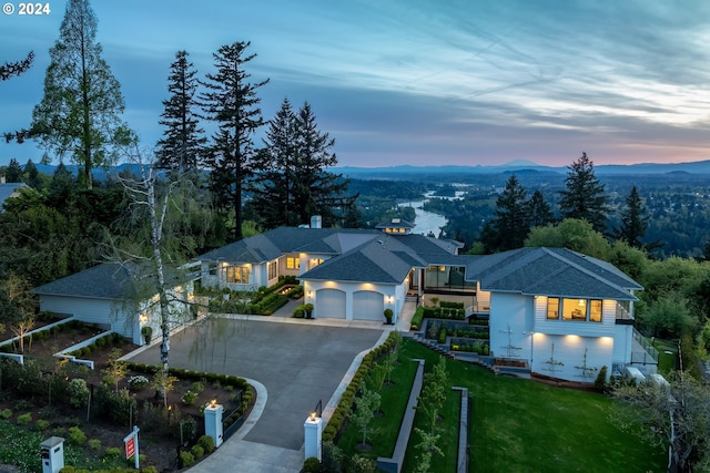 back house at dusk with a balcony, a yard, and a patio area