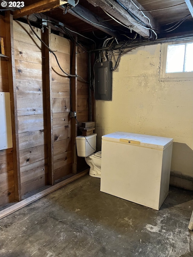 basement with electric panel and refrigerator